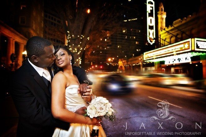 Couple embraces on Peachtree street in front of the Georgian Terrace Hotel, with the Fox Theatre Marquee as a backdrop | Georgian Terrace Hotel Wedding