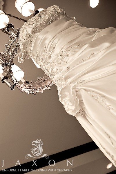 beautifully details wedding dress hangs from the chandelier | Eagle's Landing Country Club