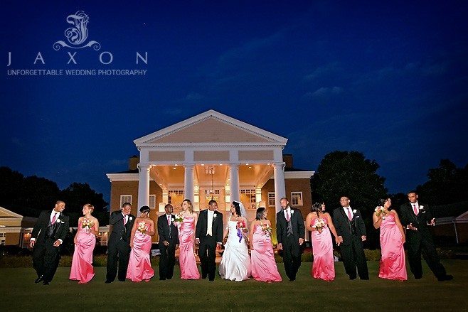 Eagles Landing Country Club wedding party walks on the lawn with the clubhouse as a backdrop in this dramatic night time photograph 