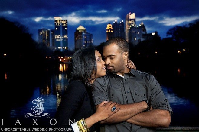 Engaged couple snuggles on the edge of Lake Clara Meer during their engagement session at Piedmont park engagement session