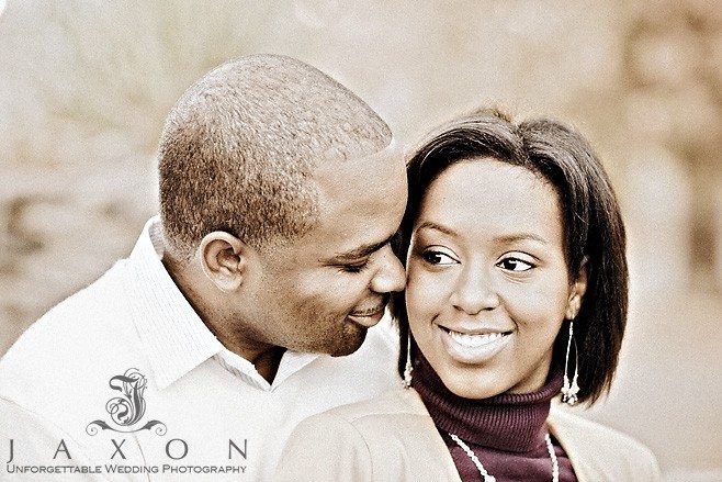 He kisses her cheek and she smiles during their engagement session at Piedmont park