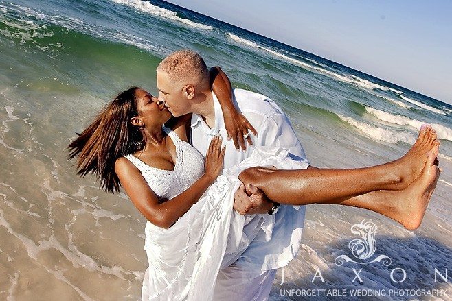 He scoops her up in his arms and kisses her as her white sundress dangles in the beach