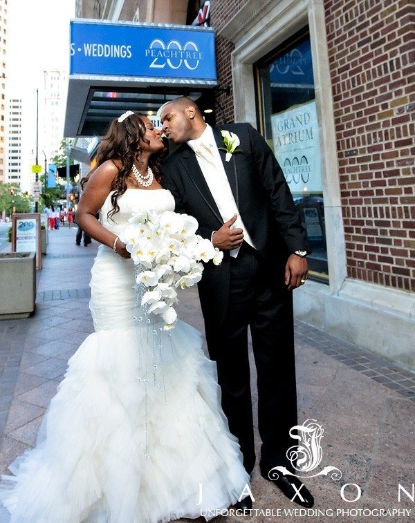 Couple kisses on sidewalk with the 200 peachtree marquee in the background, 200 Peachtree Wedding | Published by the Knot's Wedding Channel