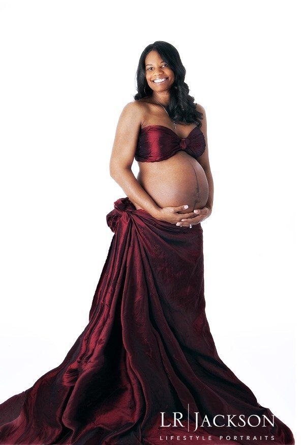 Pregnant African American female hugging her exposed belly in this maternity portrait