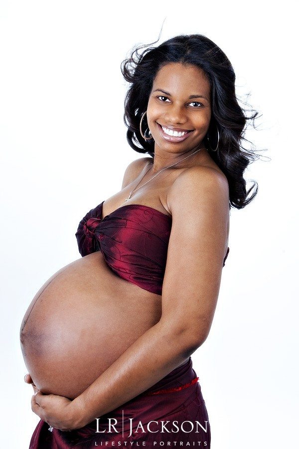 Pregnant African American Lady wrapped in crimson red  against a site backdrop