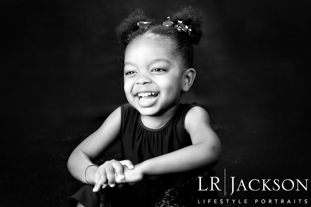 B&W portrait of 4yr old girl smiling broadly for the camera