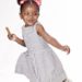 Photo of a 4yr old child in white and grey dress holding a candy bar