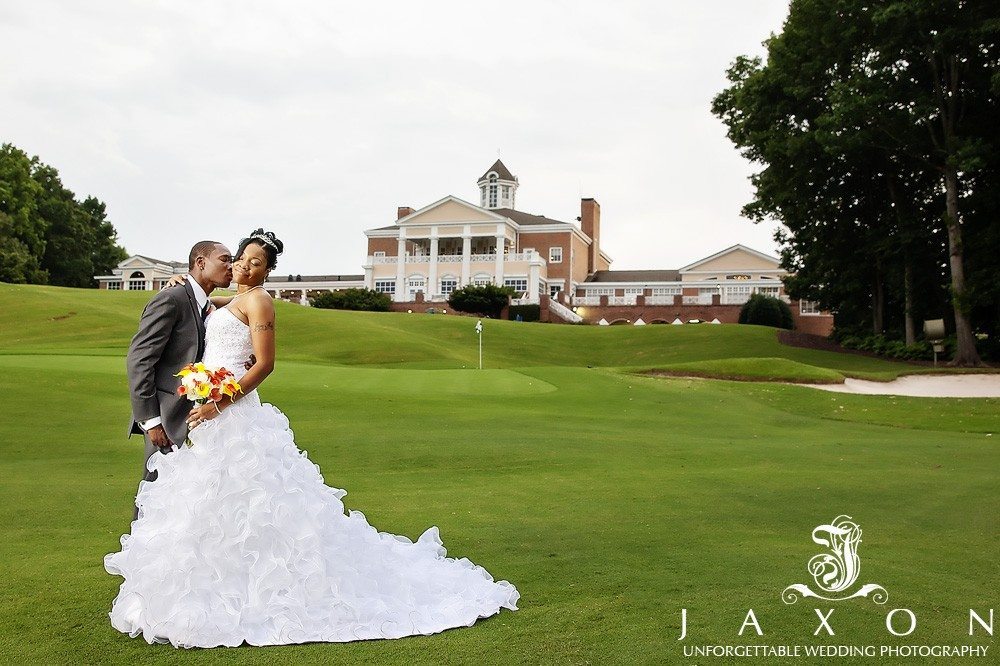 Photograph of the couple embracing on the golf course with the imposing club house in the background | Eagle's Landing Country Club Wedding