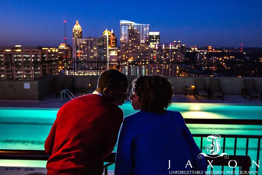 Couple gets close on the Roof top during Georgian Terrace Hotel engagement session, the midtown Atlanta sparkles in the background in this night time photograph