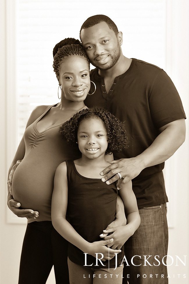 Beautiful sepia toned family portrait of African American family of three with expectant mother and young girl
