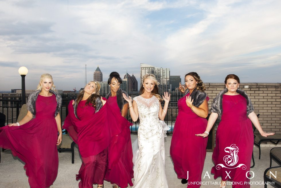 Bridal Party in ankle length maroon dresses and gray fur wraps Rooftop at the Georgian Terrace Hotel strutting their stuff, Downtown Atlanta Skyline in background