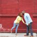 Couple kisses against a backdrop of red brick wall