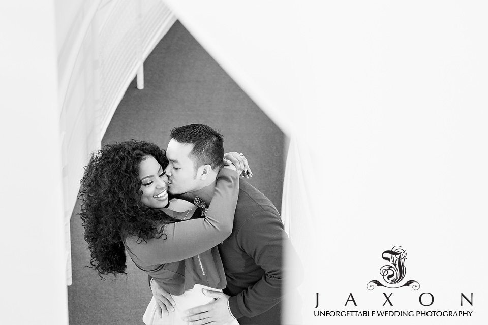 Black and white image of couple kissing through a geometric window inside the museum