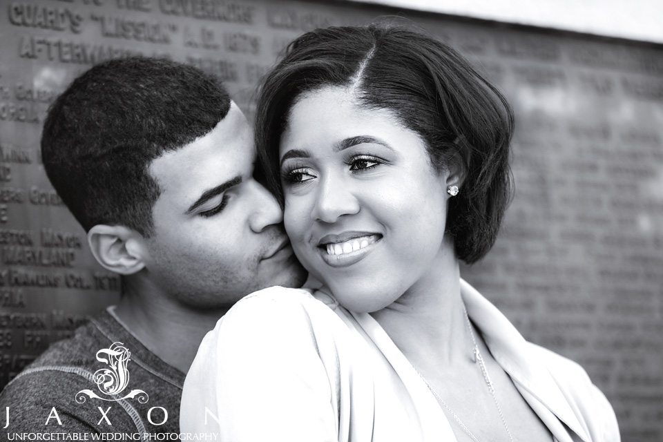 B&W portrait of a couple snuggling while leaning against the Peace Monument at Piedmont Park in Atlanta