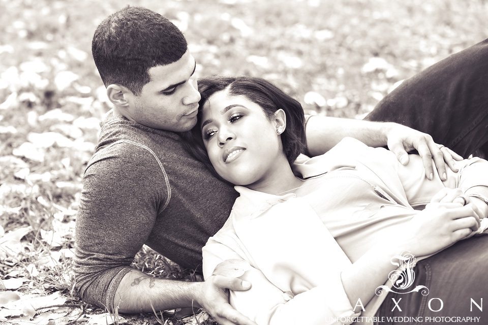 Sepia toned photo of couple laying on the grass beneath a flowing saucer magnolias, or Mulan tree