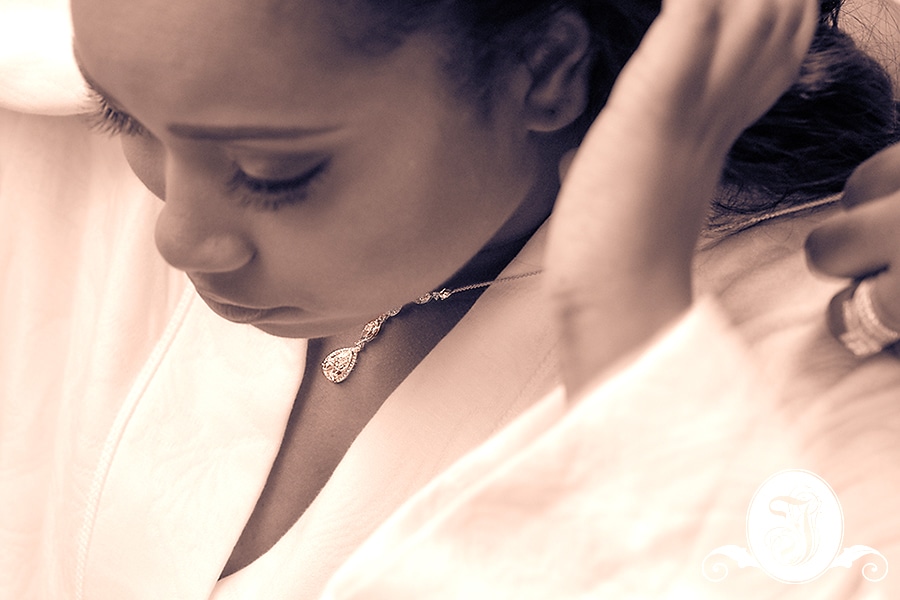 Sepia portrait of bride putting on her necklace