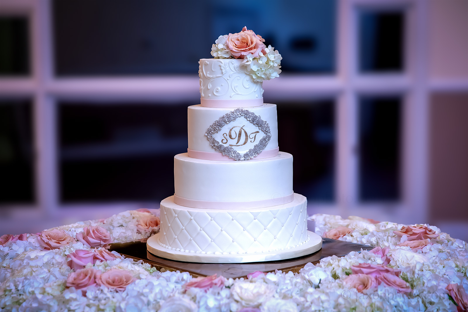 Elegant Four-Tiered White Wedding Cake with Roses and Hydrangeas