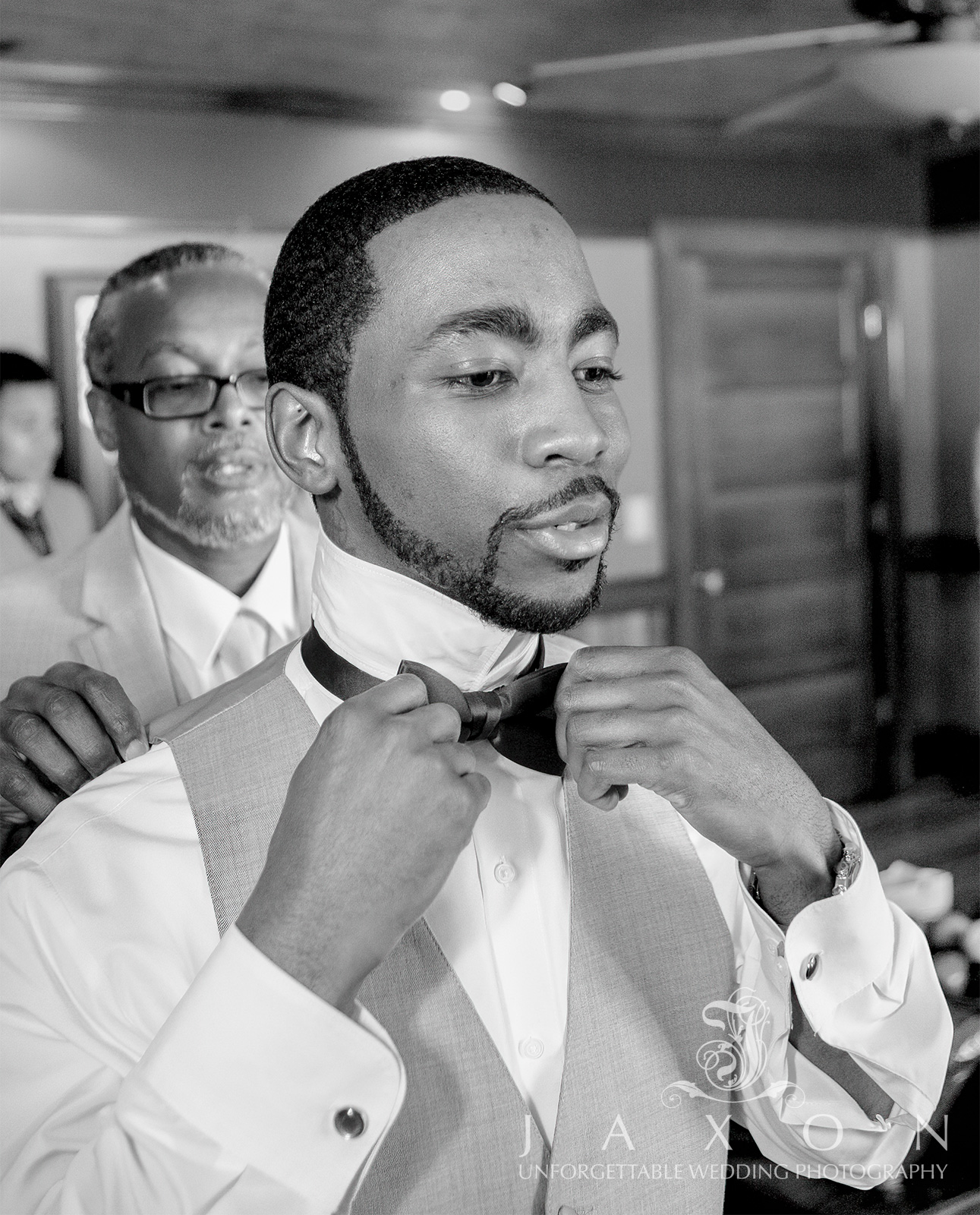 Groom getting ready for his wedding at The Carl House with attendant helping with bowtie