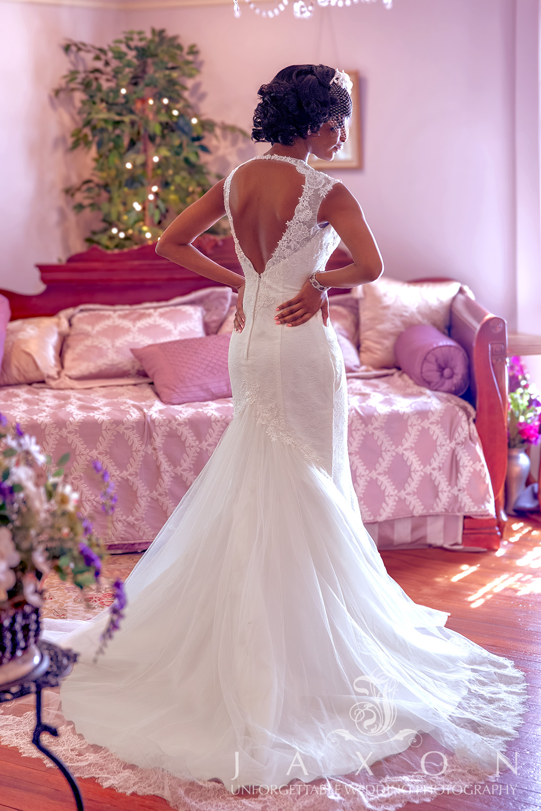 Bride checking herself out in the mirror, wearing a Galina Signature trumpet gown with a plunging V-neckline and cap sleeves, adorned with a flower-topped birdcage veil, in the bridal suite at Carl House, Atlanta.