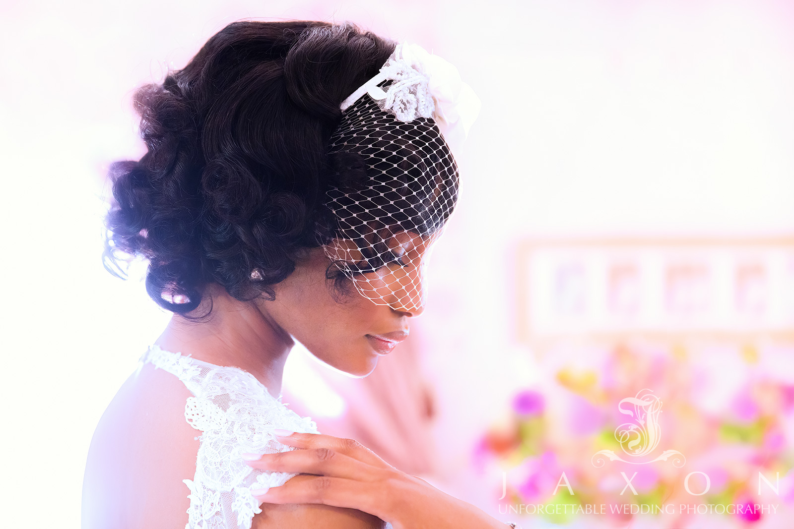 Profile headshot of a serene bride with closed eyes, wearing a birdcage veil adorned with white flowers. Her hair is elegantly styled in cascading curls, revealing a keyhole cutout on the back of her wedding dress. Photographed in natural light at Carl House Wedding and event venue in Auburn, GA.