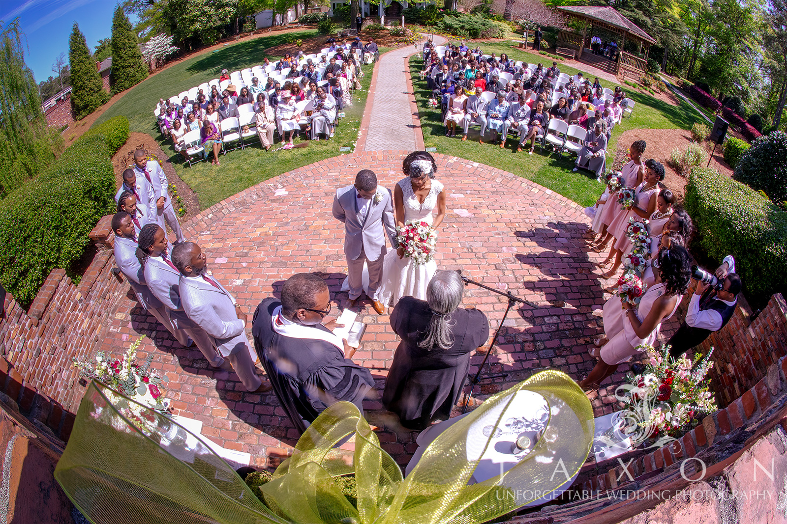 Wedding ceremony at Carl House gardens with gazebo and mansion, bridesmaids in blush dresses, and groomsmen in gray tuxedos.