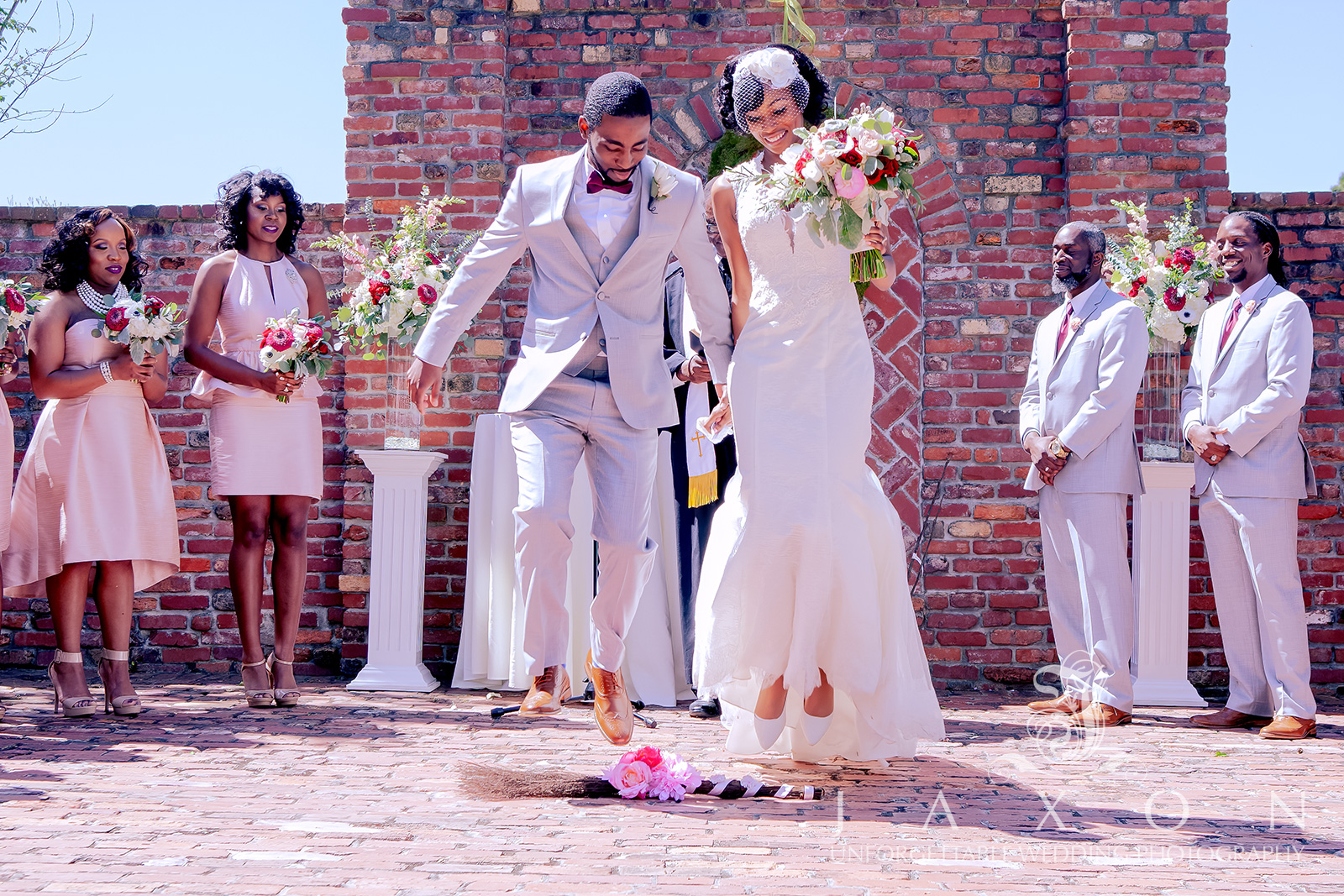 Newly married couple jumps the broom at their garden wedding ceremony.