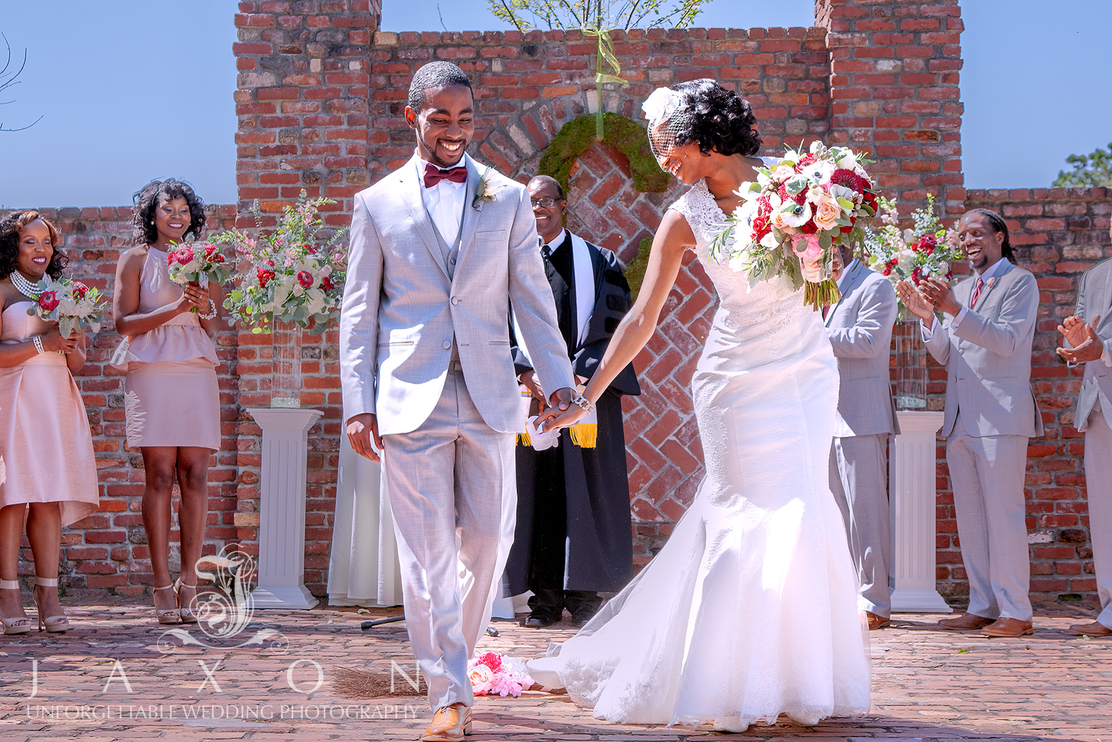 A happy couple smiles after jumping the broom at their Carl House garden wedding.