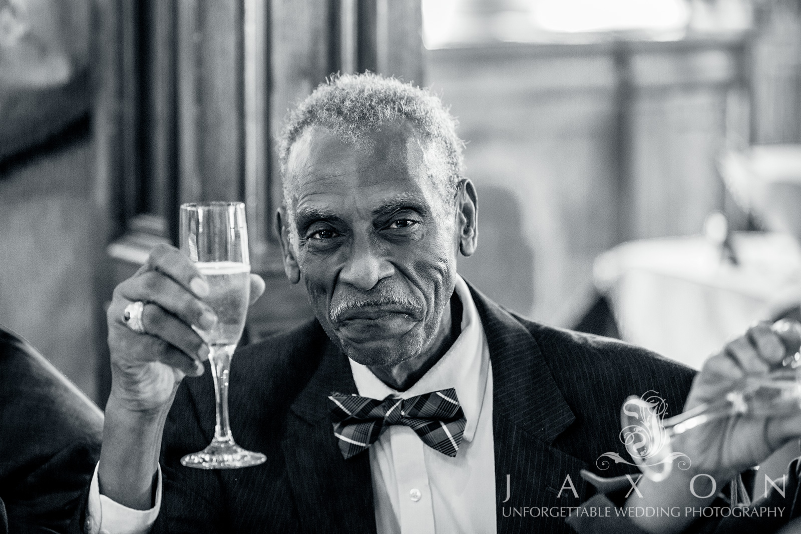 Stylish wedding guest in blue and black bowtie toasting at Carl House wedding reception, Auburn GA