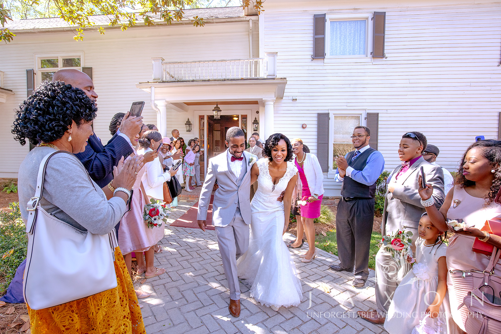 Newlyweds walking arm in arm through cheering crowd at Carl House wedding