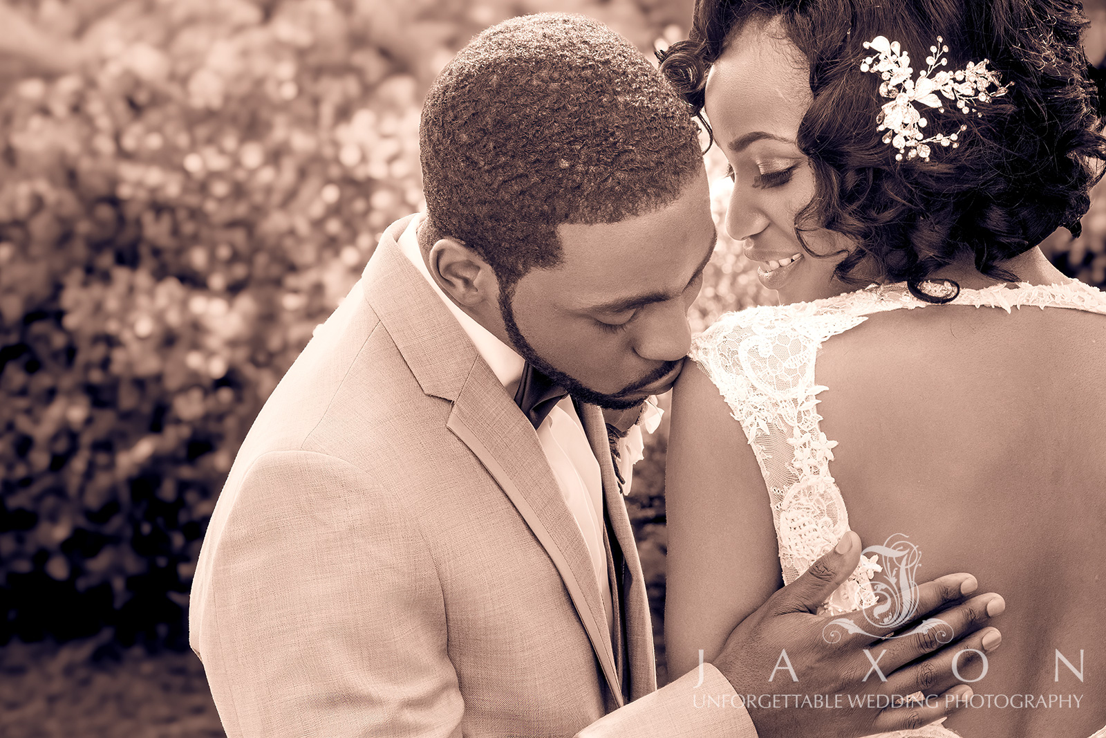 Groom kisses bride's shoulder in romantic garden setting at Carl House wedding venue.