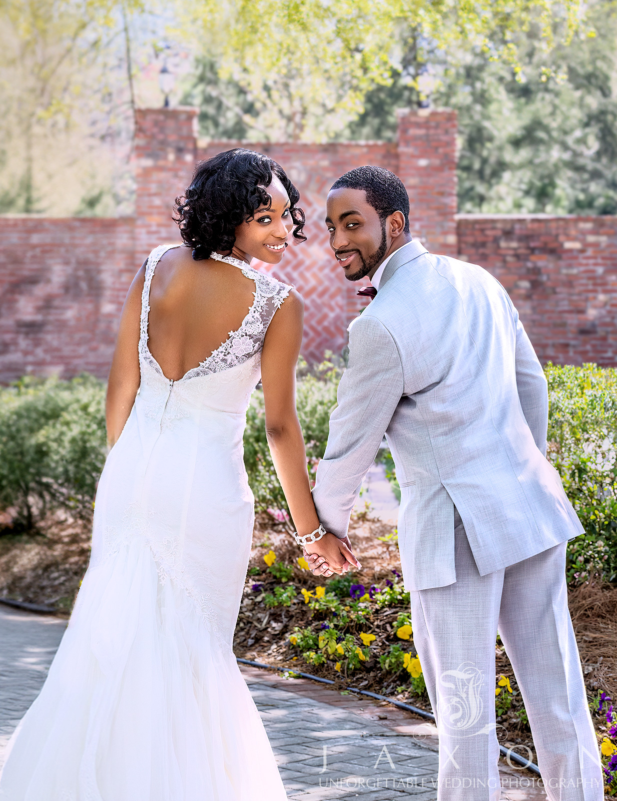 Bride and groom in garden, showcasing Galina Signature tulle-over-lace trumpet wedding gown with heart-shaped cutout, V-neckline, and cap sleeves.