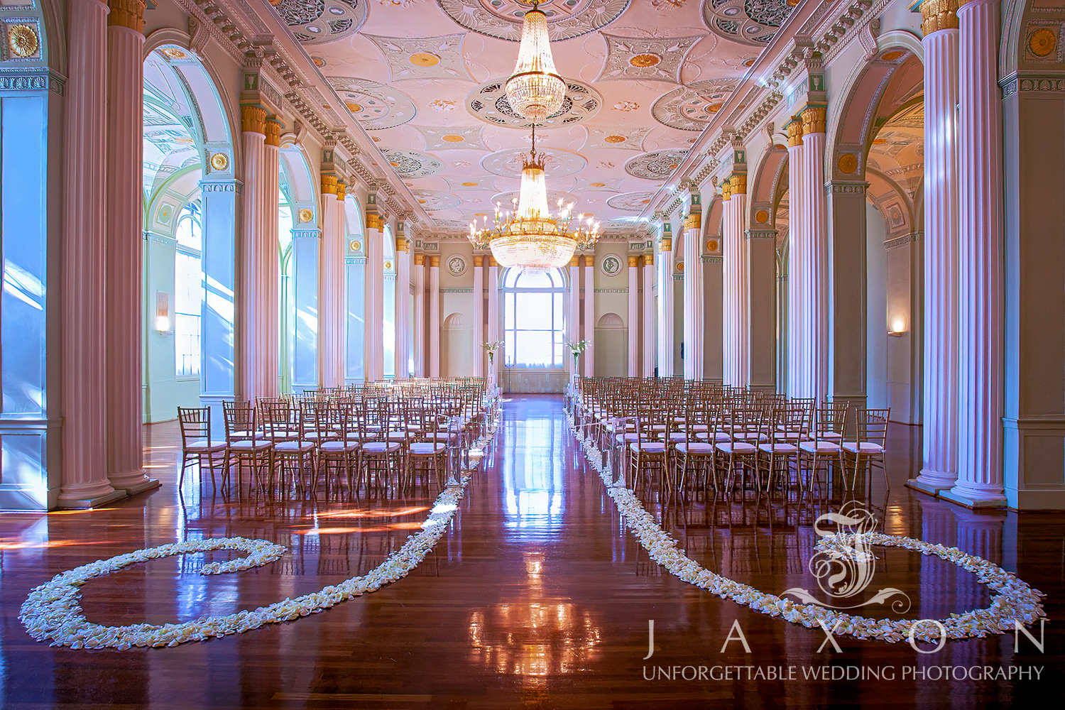 Elegant Georgian Ballroom at Biltmore Ballrooms Atlanta featuring vintage chandeliers, white Chiavari chairs, and grand Palladian window adorned with floral arrangements.